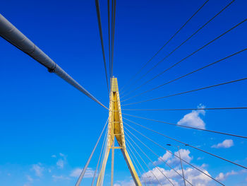 Low angle view of suspension bridge against blue sky