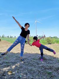 Mother and daughter with arms outstretched standing on grassy land