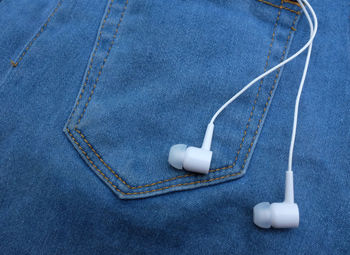 Close-up of denim and in-ear headphones