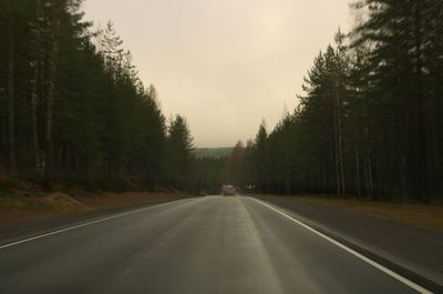 Road amidst trees in forest against sky