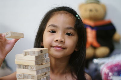 Portrait of smiling girl holding toy at home