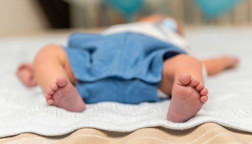 Low section of baby sleeping on bed