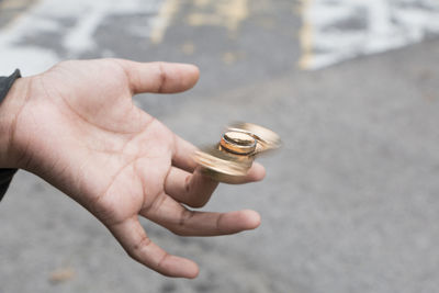 Cropped hand spinning fidget spinner on road
