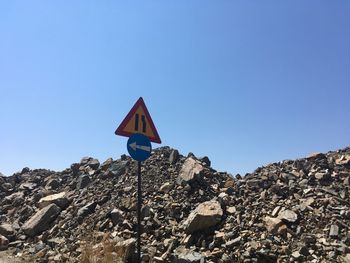 Low angle view of road sign against clear blue sky