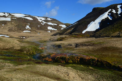 Valley with steam rising from a flowing hot spring in rural iceland.