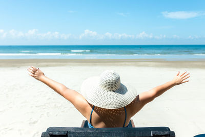 Rear view of woman wearing hat at beach against sky