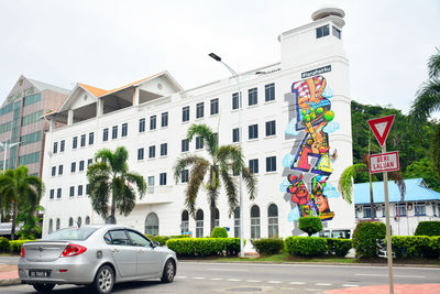 Cars on road by buildings against sky