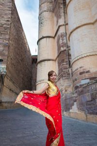 Portrait of woman in red sari standing against temple