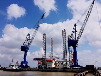 Low angle view of crane against cloudy sky