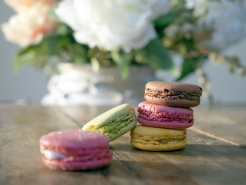 Close-up of macrons on wooden with flowers in white vase background table