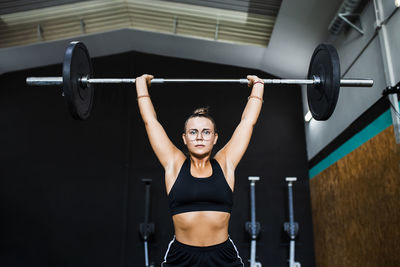 Confident female athlete lifting deadlift in gym