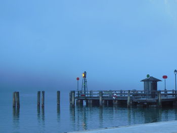 Pier over river against sky during foggy weather