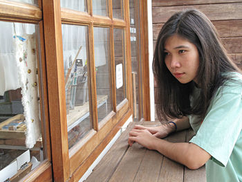 Portrait of beautiful young woman sitting on window