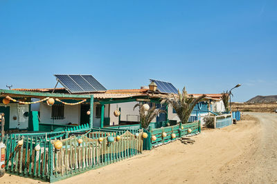 Old dwelling house facades with solar cells on roofs against sandy road in fuerteventura in canary islands spain