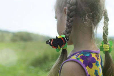 Dreamy 5-6 years old girl with a butterfly on her hair looking forward on the horizon