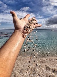 Cropped image of person standing by sea against sky