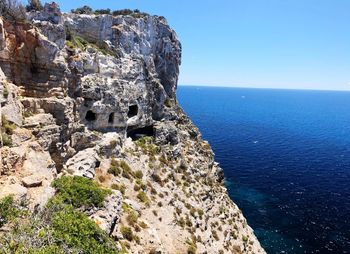 Rock formations by sea against blue sky