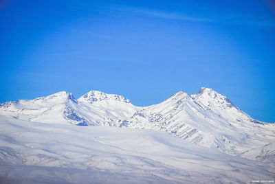 Scenic view of snowcapped mountains against clear blue sky