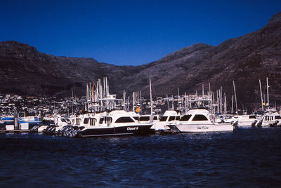 Sailboats moored in sea against clear blue sky