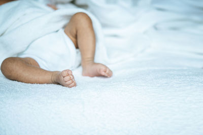 Midsection of child lying on bed