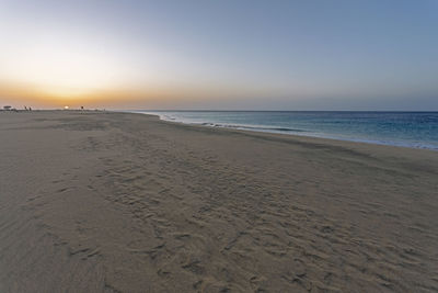 Scenic view of beach against clear sky during sunset