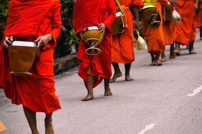 Low section of monks walking on street in city