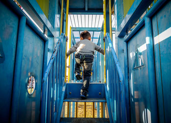 Rear view of boy playing in jungle gym at playground