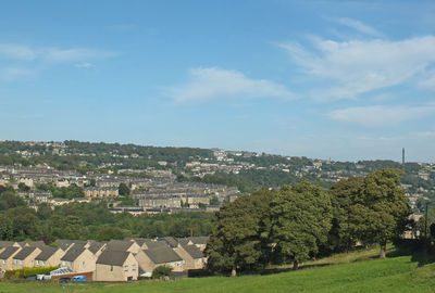 Trees and buildings on field against sky