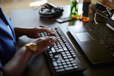 Midsection of businesswoman typing on keyboard at desk in creative office