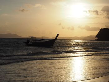 Silhouette boat in sea against sky during sunset