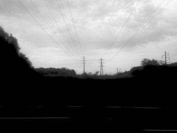 Electricity pylon against cloudy sky