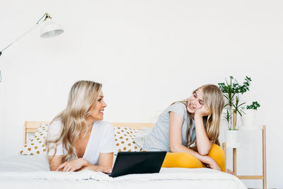 Young woman using phone while sitting on laptop