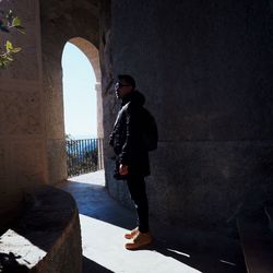 Full length of man standing by wall of building