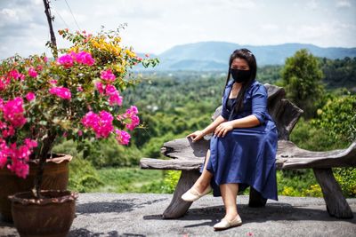 Full length of woman sitting at park against sky