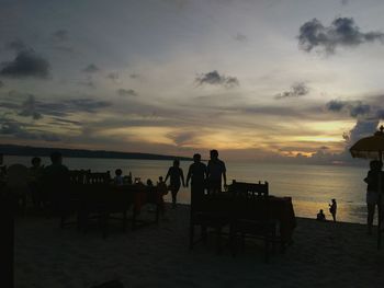 Silhouette people on beach against sky during sunset