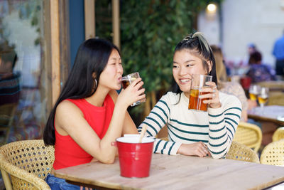 Young woman using mobile phone while sitting at restaurant