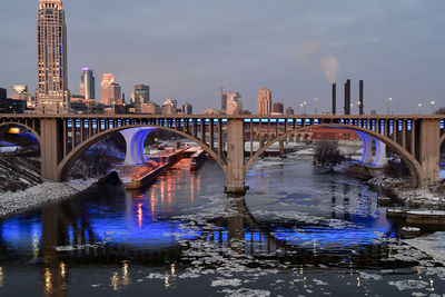 Illuminated bridge over river in city at night