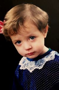 Close-up portrait of cute baby girl over black background