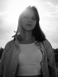 Portrait of young woman standing against sky