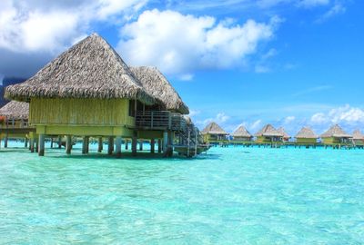 Stilt houses by lake against sky