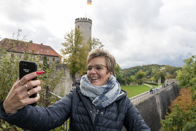 Tourist woman in front of a tourist attraction  taking a selfie with mobil phone