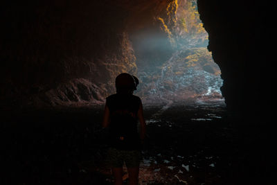 Rear view of silhouette man standing in cave