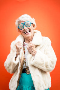 Portrait of smiling senior woman against orange background