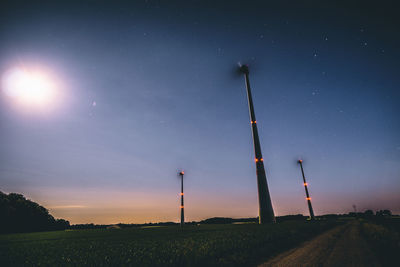 Wind turbines on field against sky at night