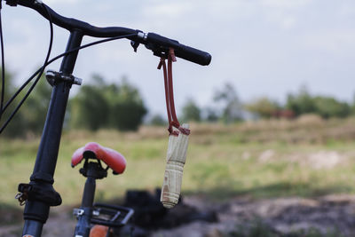 Close-up of bicycle hanging on field against sky