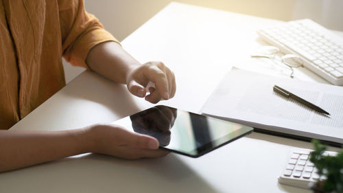 Midsection of woman using smart phone on table