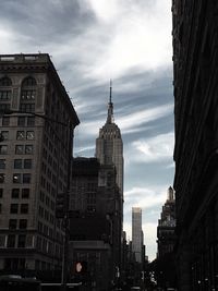 Low angle view of skyscrapers against cloudy sky