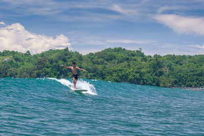 Man surfing in sea against sky