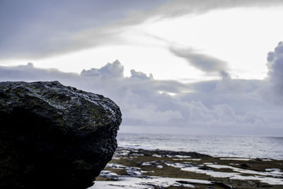 Rock formation on beach against sky