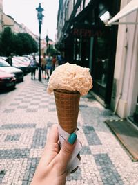 Cropped hand of woman holding ice cream cone on street